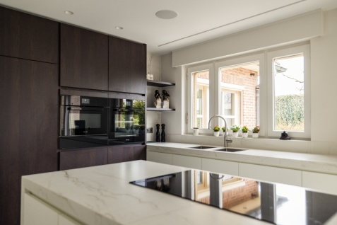 keuken met donkerbruine kasten en wit keukeneiland